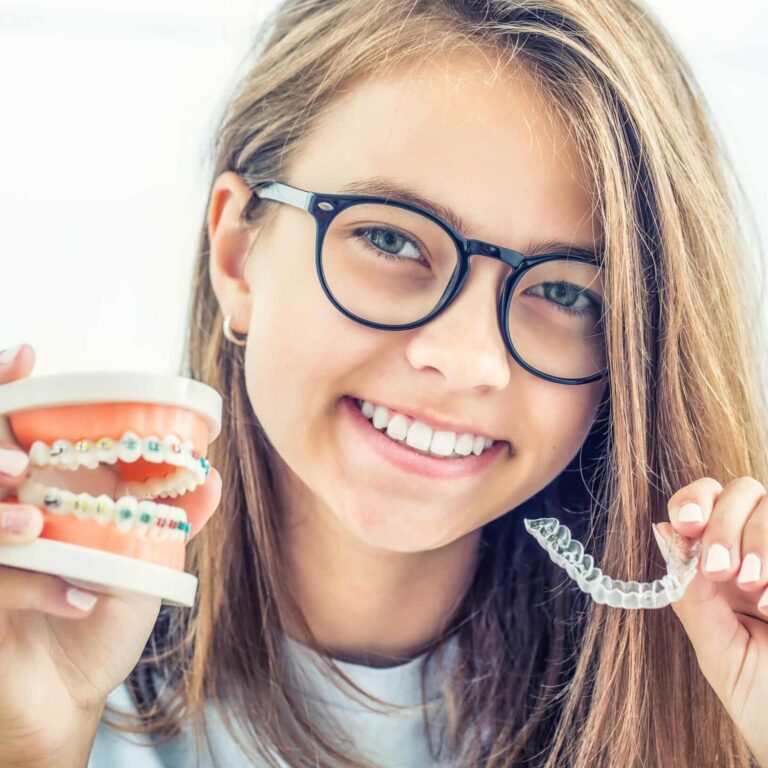 Dental invisible braces or silicone trainer in the hands of a young smiling girl. Orthodontic concept - Invisalign.